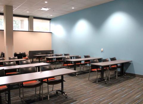 Photograph of meeting room showing 2 columns of 4 tables, each with 2 chairs.