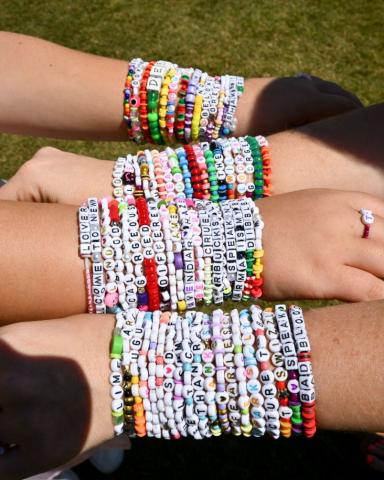 four arms with many friendship bracelets stacked on each arm