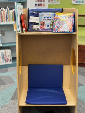 Wooden seating area that is covered by a shelf displaying books about social emotional learning