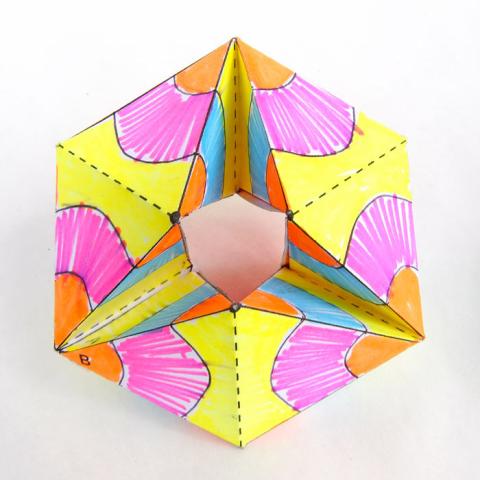 a six-sided folded paper craft with pink and yellow flowers drawn on it