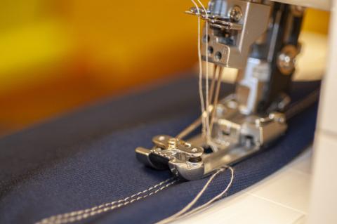 Close up image of sewing machine sewing denim