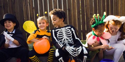 Children dressed in Halloween costumes sitting together.