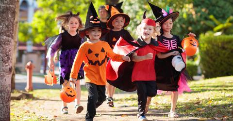 Children in Halloween costumes trick-or-treating outdoors.