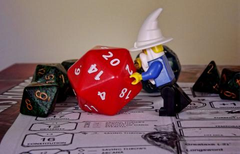 Picture of a lego wizard pushing a d-20 
