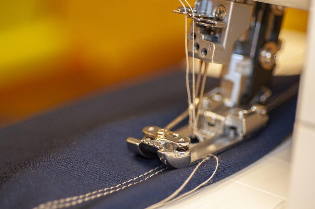Close up image of sewing machine sewing denim
